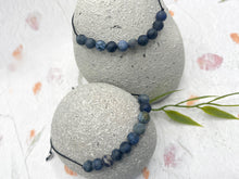 Load image into Gallery viewer, Hand wearing dumortierite stress relief bracelet demonstrating adjustable fit
